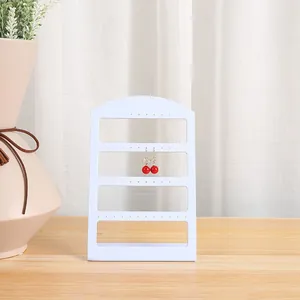 Soporte de exhibición de pendientes blanco minimalista de cuatro niveles en mesa de madera