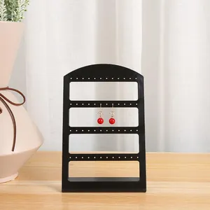 Vista detallada de un soporte para pendientes negro minimalista sobre una mesa