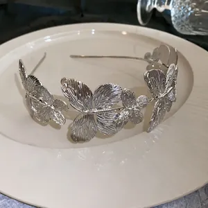 Detailed view of elegant silver metal butterfly headband on a white ceramic plate.
