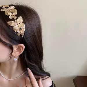 Close-up detail of an elegant gold metal butterfly headband on model's dark hair