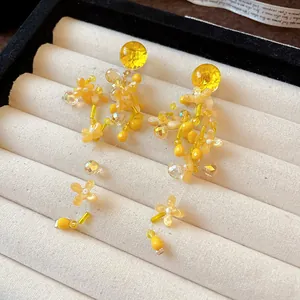 Primo piano di eleganti orecchini a nappa floreale gialla su vassoio per gioielli