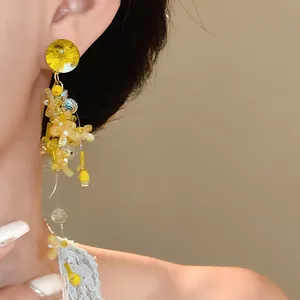 Dettaglio di eleganti orecchini a nappa con petali gialli e ago in argento sul modello