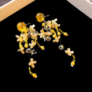 Dettaglio di orecchini a nappa con fiori gialli fatti a mano e gocce di cristallo su velluto