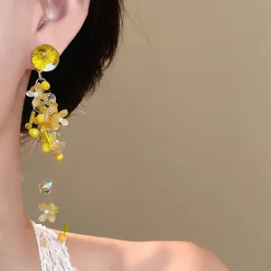 Vista dettagliata di orecchini con nappe di petali gialli indossati da una modella