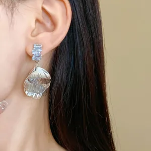 Primo piano di eleganti orecchini a petalo d'argento spazzolato con zirconi