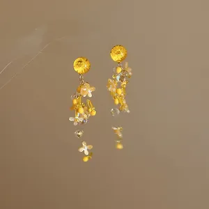 Vista dettagliata di eleganti orecchini con nappe a petalo giallo e perline.