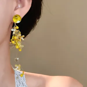 Vista ravvicinata di eleganti orecchini a nappa con petali di fiori gialli e ago d'argento