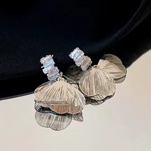Primo piano di eleganti orecchini a petalo in metallo spazzolato con pietre di zircone