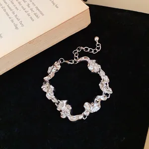 Primer plano de una pulsera de metal plateado arrugado sobre un fondo de terciopelo