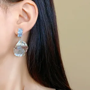 Primo piano di eleganti orecchini a petalo d'argento spazzolato con zirconi blu