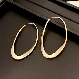 Detailed view of oversized geometric hollow oval earrings in a polished gold finish.