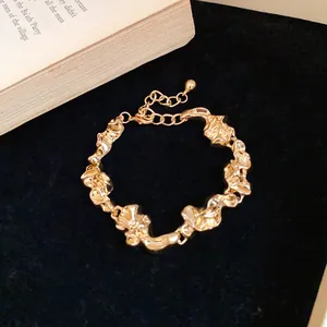 Primer plano de una pulsera de metal dorado con un diseño retorcido y arrugas irregulares
