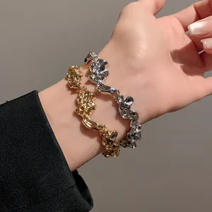 Vista detallada de dos pulseras metálicas irregulares y arrugadas en color oro y plata