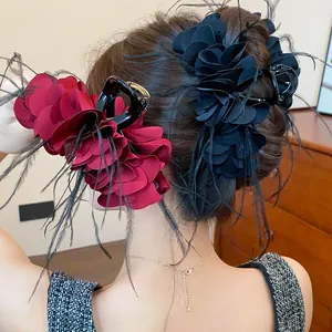 Detailansicht von zwei Rosen- und Feder-Haarklammern in einer eleganten Hochsteckfrisur