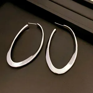 Macro view of silver-toned hollow oval hoop earrings with polished metallic finish.