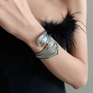 Detail shot of a chunky silver irregular twisted open cuff bangle worn on a female wrist
