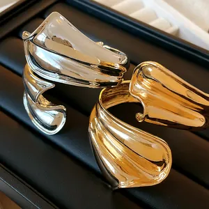Macro view of irregular twisted metallic cuff bracelets with high-gloss gold and silver finishes
