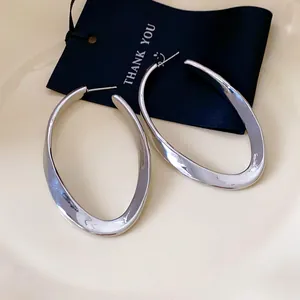 Detailed close-up view of silver-colored irregular oval hollow geometric hoop earrings style