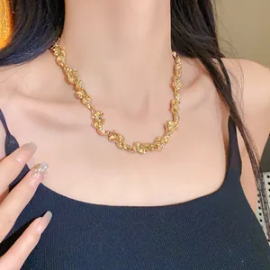 Primer plano de un collar dorado arrugado en una modelo que lleva una camiseta negra