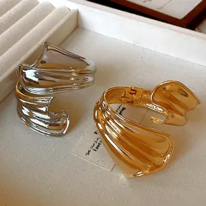 Detail of chunky twisted irregular open bangles in gold and silver metal finishes