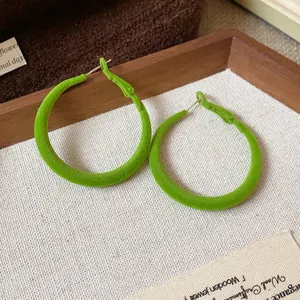 Primo piano di orecchini a cerchio floccati verde vibrante con eleganti dettagli.
