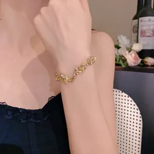 Detalle de brazalete de metal dorado arrugado irregular en la muñeca de una mujer en un ambiente