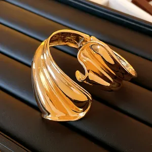 Detail view of a chunky gold twisted irregular cuff bracelet on a black display