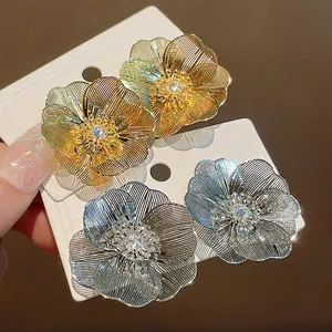 Dettaglio di orecchini a fiore in oro e argento con petali a rete e centri in zircone