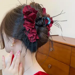Detailansicht einer eleganten bordeauxfarbenen Rosen-Haarklammer mit Federakzenten