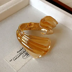 Macro detail of chunky gold irregular open cuff bracelet with polished metallic finish