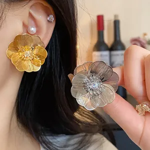 Dettaglio di orecchini a fiore placcati oro e argento con zirconi scintillanti