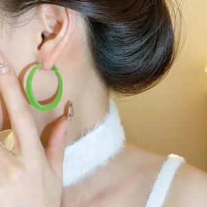 Primo piano di orecchini a cerchio floccati verde lime con texture vellutata invernale
