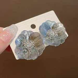 Dettaglio elegante di orecchini a lobo a fiore placcati in oro con petali a rete e zircone