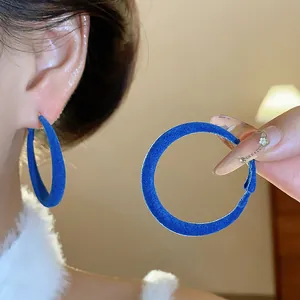 Primo piano di orecchini a cerchio floccati blu con morbida trama in velluto e argento.