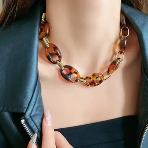 Detail shot of a vintage tortoise shell resin chain necklace with gold links on a model.