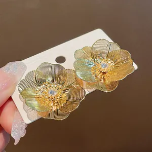 Vista dettagliata di squisiti orecchini a fiore in filo placcato oro con centri in zircone
