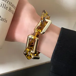 Close-up detail of retro leopard print and gold metal chain bracelet worn on a wrist
