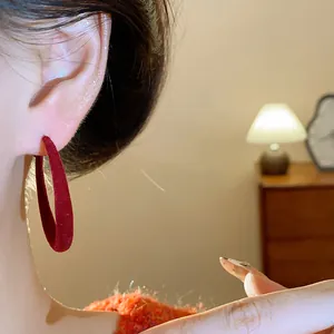 Primo piano di un orecchino a cerchio floccato rosso indossato in un interno accogliente