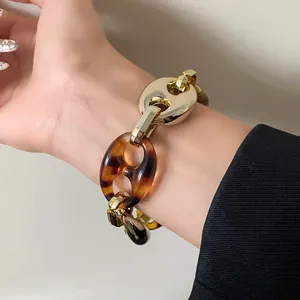 Chunky tortoise shell and gold chain bracelet on wrist detail view
