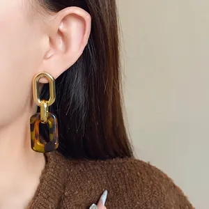 Close-up detail of vintage leopard print and gold chain link earrings worn on model