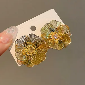 Dettaglio ravvicinato di orecchini a lobo a fiore placcati in oro con accenti di zirconi