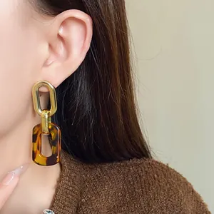Close-up of retro leopard print chain earrings worn by a model in a stylish studio setting