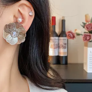 Primo piano di un grande orecchino a fiore d'argento con zircone centrale su una modella