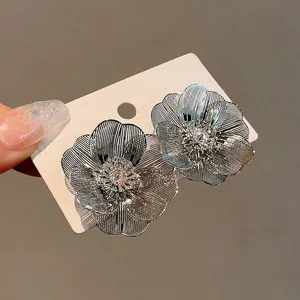Primo piano di orecchini a fiore argentati con pietre di zircone brillanti.