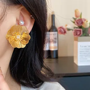 Dettaglio di orecchini a fiore placcati oro oversize con zircone centrale