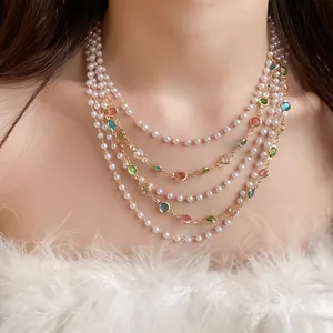 Detail view of a multi-layer pearl necklace with colorful gemstones on a model