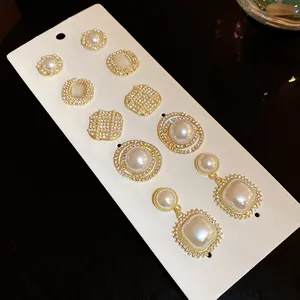 Detailed close-up of elegant gold-toned pearl and rhinestone earring set on a display card