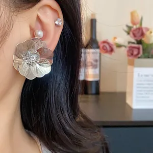 Dettaglio di orecchini a forma di fiore d'argento con zircone centrale e perla