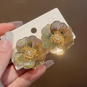Dettaglio ravvicinato di orecchini a fiore placcati in oro con zircone centrale lucente
