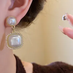 Macro detail of French vintage pearl earrings with rhinestone borders on model's ear